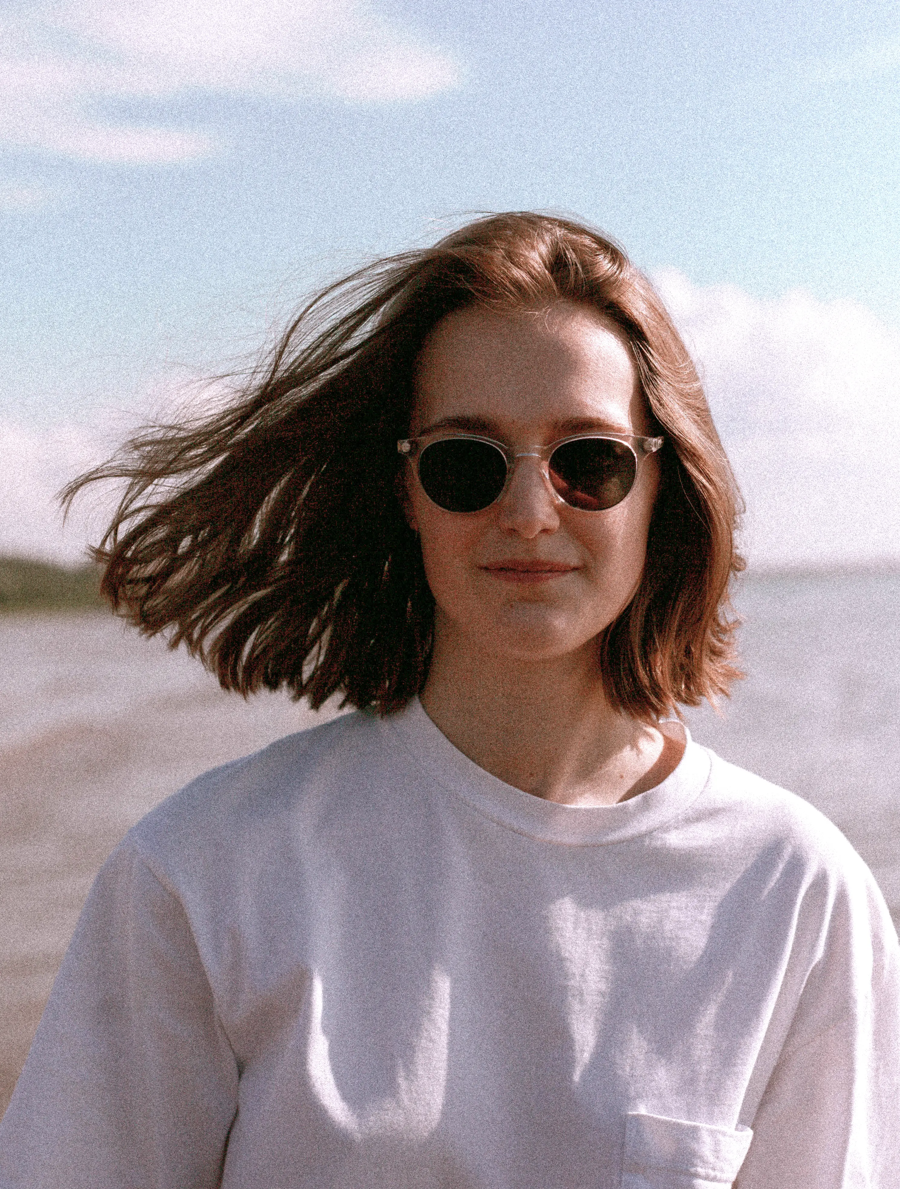 Светлокожая девушка с каре в тёмных очках на фоне моря, чёрно-белое фото